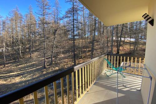 a balcony with a chair and a view of the woods at 06CO beautiful apartment at the foot of the slopes with balcony in Valberg