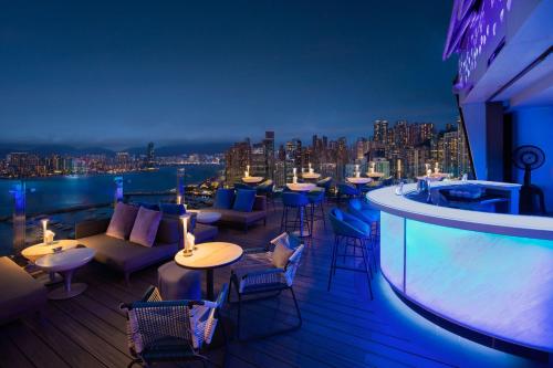a rooftop bar with tables and chairs and a view of the city at The Park Lane Hong Kong, Autograph Collection in Hong Kong