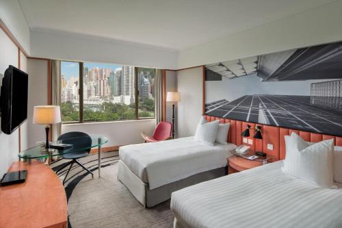 a hotel room with two beds and a desk at The Park Lane Hong Kong, Autograph Collection in Hong Kong