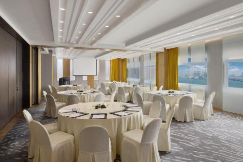 a banquet room with tables and chairs and a screen at The Park Lane Hong Kong, Autograph Collection in Hong Kong