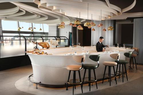 a man standing at a bar in a restaurant at The Park Lane Hong Kong, Autograph Collection in Hong Kong
