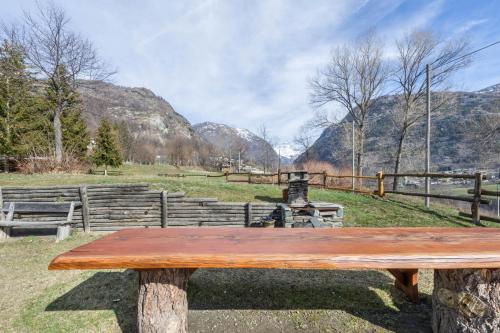 a wooden bench sitting in a field with mountains at Chalet complet in Antey-Saint-André