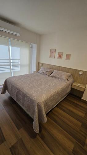 a bedroom with a large bed and a wooden floor at Monumento y Río - Parking privado con costo adicional in Rosario