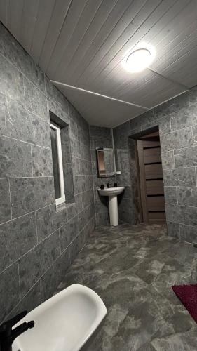 a bathroom with a sink and a bath tub at Cottage Zhelikhovskykh in Tatariv