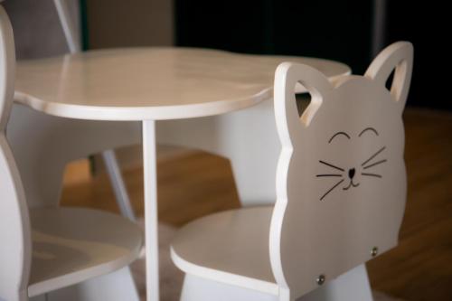 a white chair next to a table with a cat painted on it at UBYTKO - Apartment in Blahová - Experience Rye Island in Blahová