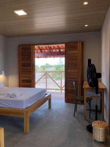 a bedroom with a bed and a desk and a window at Casa Vento - 2 Andares e Cozinha in Luis Correia