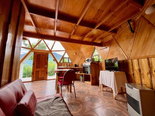 a living room with a table and a kitchen at Domo Huepil in Pichare