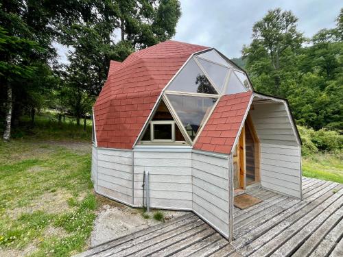 a small house with a red roof on a deck at Domo Huepil in Pichare