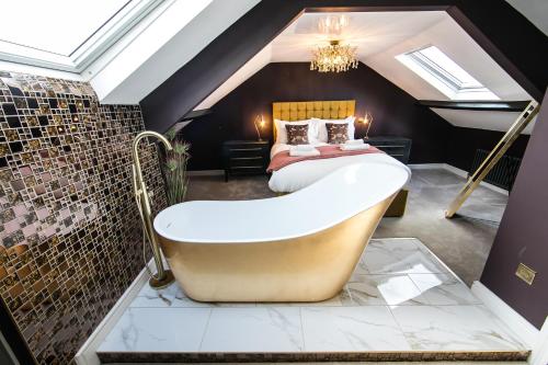 a bathroom with a bath tub and a bed at Serenity Suites in Whitby