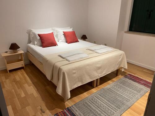a bedroom with a white bed with red pillows at Retiro Do Tejo in Malpica