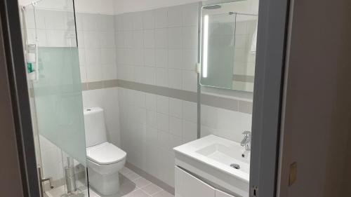 a white bathroom with a toilet and a sink at Retiro Do Tejo in Malpica