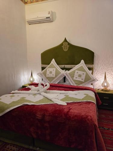 a bed with a red blanket with a bow on it at Dar Khmissa Fes-Luxury Stay Fes Medina in Fès