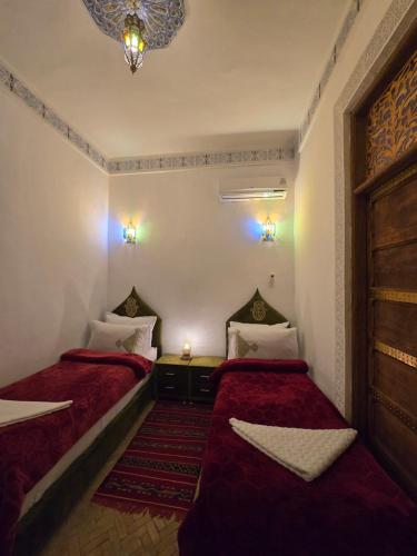 two beds in a small room with red sheets at Dar Khmissa Fes-Luxury Stay Fes Medina in Fès