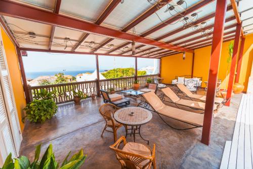 a patio with a couch and tables and chairs at The Colonial Guest House in São Filipe
