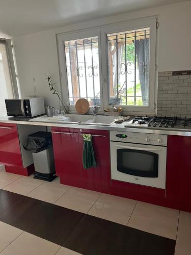 Il comprend une cuisine équipée d'une cuisinière rouge et blanche. four supérieur dans l'établissement Belle chambre à louer, à Argenteuil