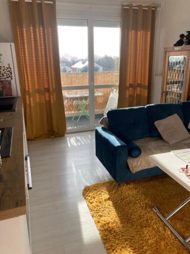 a living room with a blue couch and a balcony at Appartement calme et ensoleillé in Hérouville-Saint-Clair