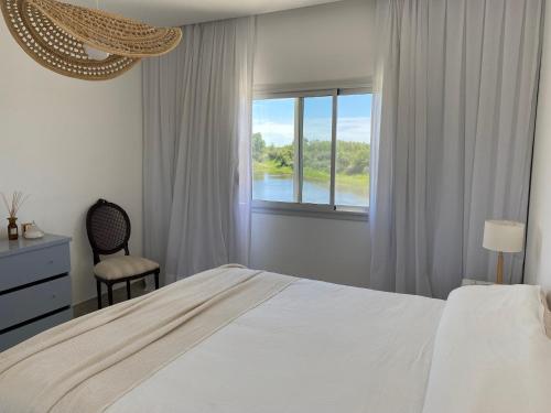 a white bedroom with a bed and a window at Casa en barrio privado en Escobar, laguna y pileta in Belén de Escobar