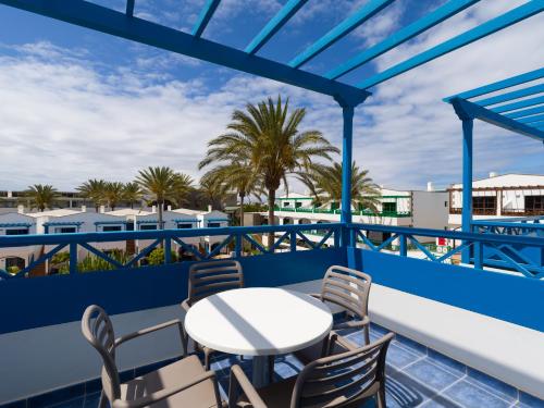 a balcony with a table and chairs and palm trees at Hotel Mirador Papagayo by LIVVO in Playa Blanca