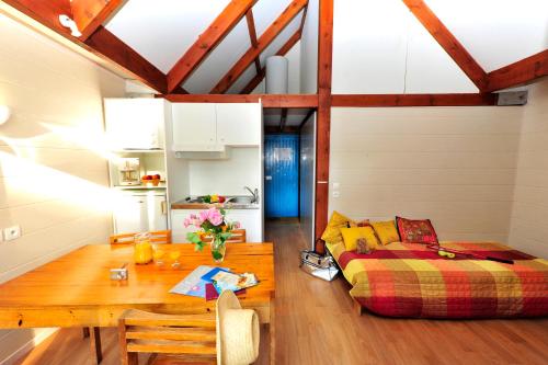 a living room with a bed and a wooden table at VTF Les Bruyères in Maubuisson