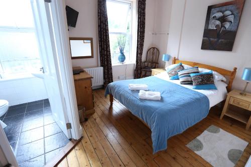 a bedroom with a bed with blue sheets and a bathroom at An Caislean incorporating Corratavey in Ballycastle
