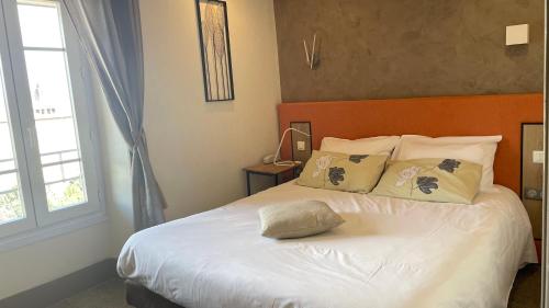 a bedroom with a bed with white sheets and pillows at Hôtel Gambetta in Lons-le-Saunier