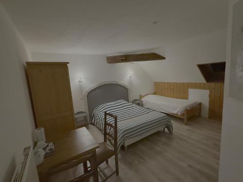 une petite chambre avec deux lits et une table dans l'établissement Auberge du Comtois, à Pont-dʼHéry