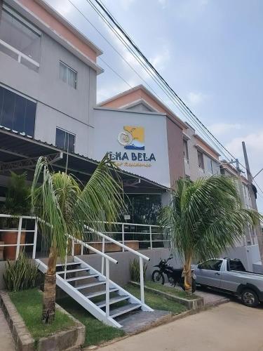 a hotel with palm trees in front of a building at Flat Novo Todo Climatizado em Alter do Chão in Alter do Chao
