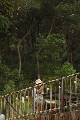 a man wearing a hat looking through a fence at Quin House in Sóc Sơn