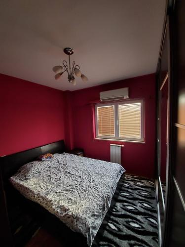a bedroom with a bed and a red wall at Apartman Aylin in Tuzla