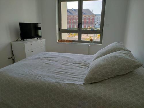 - un lit avec deux oreillers et une télévision dans une chambre dans l'établissement La Poulouchette Berck appartement 200m de la plage, à Berck-sur-Mer