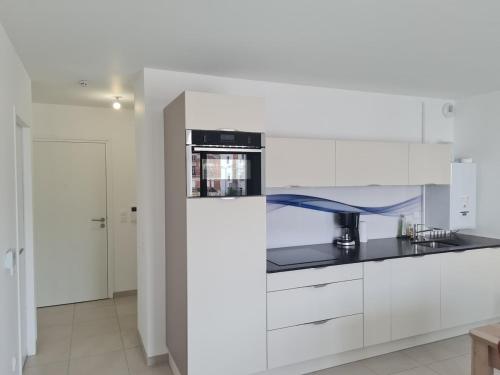 une cuisine avec des armoires blanches et un comptoir noir dans l'établissement La Poulouchette Berck appartement 200m de la plage, à Berck-sur-Mer