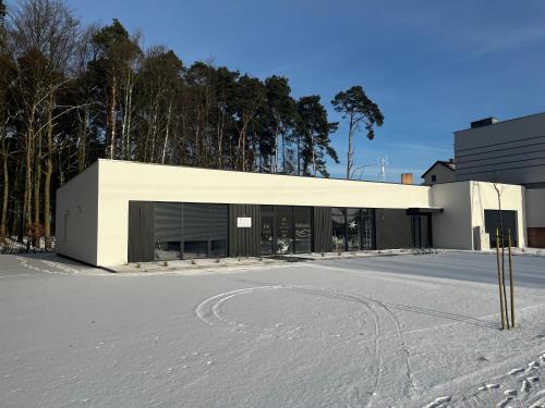 a large white building in the snow with trees at Apartamenty pod sosną in Zakrzewo