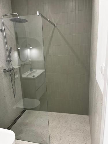 a bathroom with a glass shower with a sink at Apartamenty pod sosną in Zakrzewo