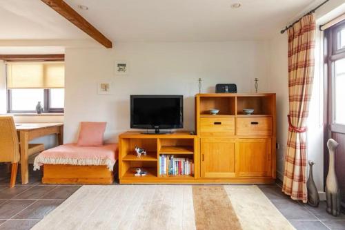 a living room with a television on a wooden cabinet at Trelowen Cottage in Callington