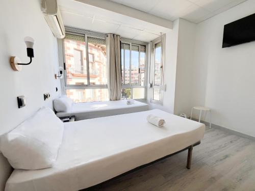 a white room with a bed and a window at Sleep&Go in Alicante