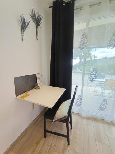 une table et une chaise dans une pièce avec une fenêtre dans l'établissement Suite indépendante - Les Lavandes, à Peyruis