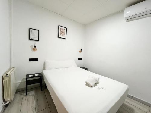 a white bedroom with a bed and a table at Sleep&Go in Alicante