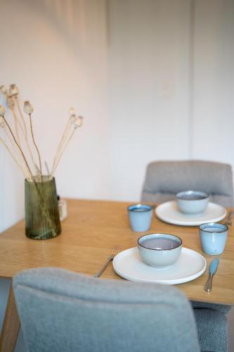 a wooden table with blue bowls and plates on it at Studio Herman met buitenterras in Kapellenbos, bij de Kalmthoutse Heide in Kapellen