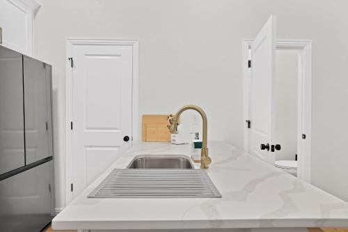 a white kitchen with a sink and a faucet at Victory Villa - Lux Townhome Walk 2 Globe Life - Rangers & Cowboys Stadiums in Arlington