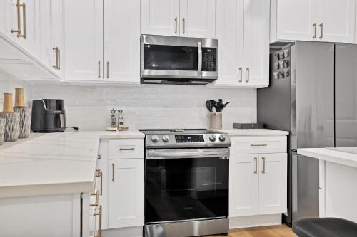 a kitchen with white cabinets and a stove and a microwave at Victory Villa - Lux Townhome Walk 2 Globe Life - Rangers & Cowboys Stadiums in Arlington