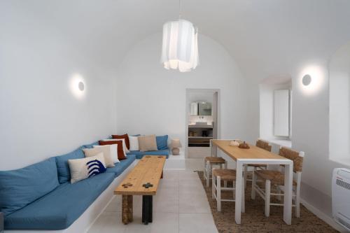a living room with a blue couch and a table at Kalyva Cycladic house - Oia Santorini in Oia