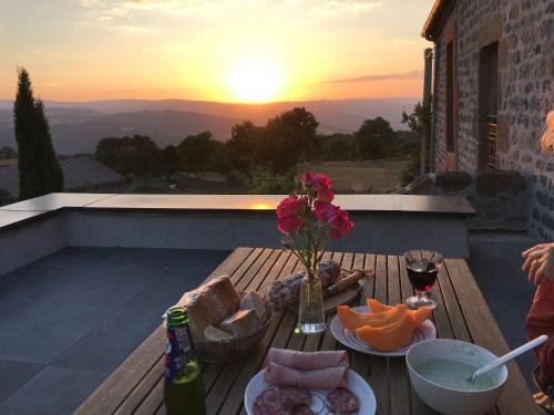 - une table avec un vase de fleurs sur le balcon avec un coucher de soleil dans l'établissement La Béraine, à Saint-Bérain