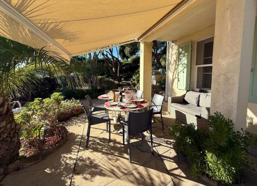 un patio avec une table et des chaises sur un porche dans l'établissement Authentique Villa le Cactus entièrement rénovée climatisée proche des plages du centre du Lavandou et du supermarché, à Bormes-les-Mimosas