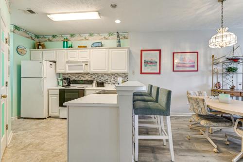a kitchen with white appliances and a table with chairs at 4 Mi to Ocean Myrtle Beach Condo with Resort Perks in Myrtle Beach