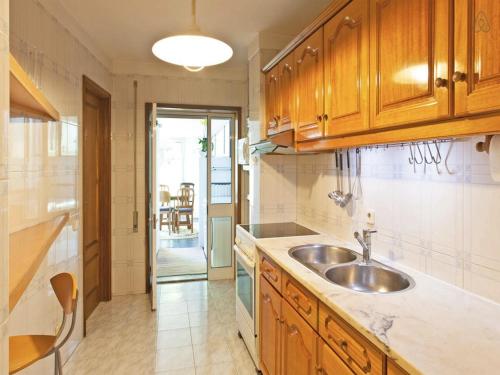 una cocina con armarios de madera y fregadero en Apartment with Private Garden, en Oporto