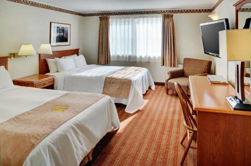 um quarto de hotel com duas camas e uma secretária em Lakeview Inns & Suites - Brandon em Brandon