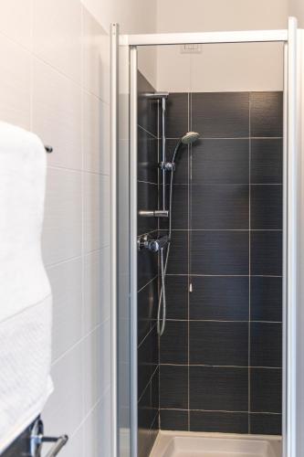 a shower in a bathroom with black tiles at Il Giardino Di Lory in Vercana