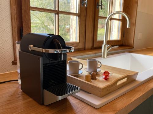 a coffee machine on a kitchen counter with two cups at Le Manoir du Perroy in Saint-Wandrille-Rançon