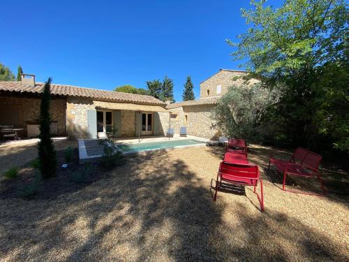 a yard with two red chairs and a house at Mazet Arlequine in Eygalières