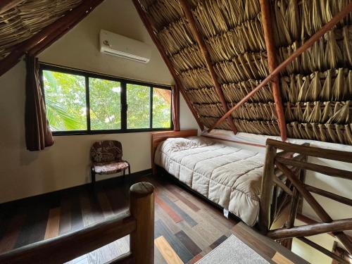 a room with a bed in a thatched room at Embajada Universal By La Eufemia Group in Huay Pix